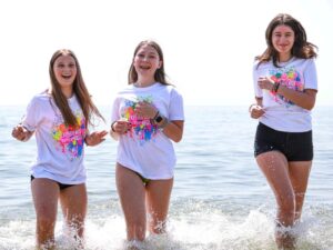 ragazze che corrono in spiaggia durante un camp estivo